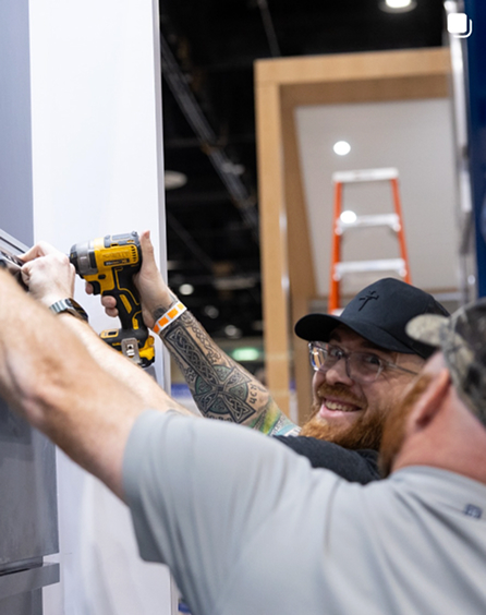 An installer fastening a Nichiha panel with a drill during a booth build