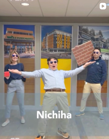 Three team members posing with a Nichiha brick panel sample in the office
