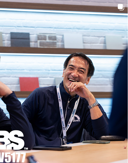 A Nichiha colleague laughing during a meeting beside a wall of panel samples