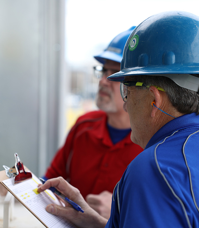 Two Nichiha team members in hard hats reviewing an inspection checklist at a jobsite