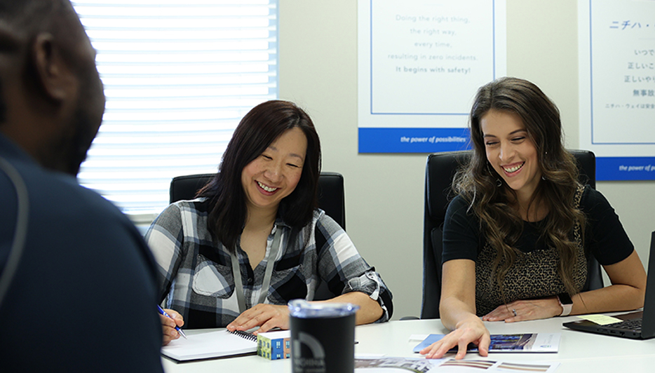 Two Nichiha colleagues laughing together during a meeting at the office