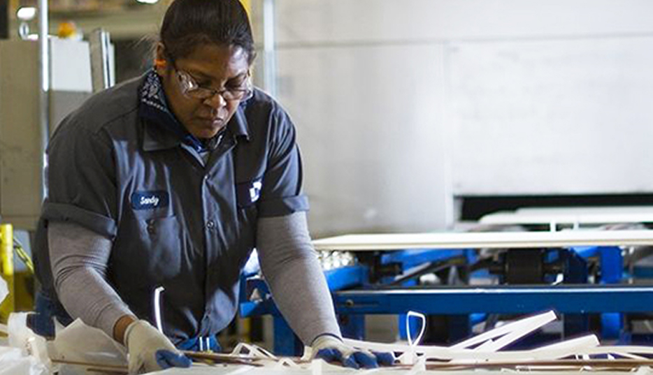 A production associate inspecting fiber cement trim pieces on the production line