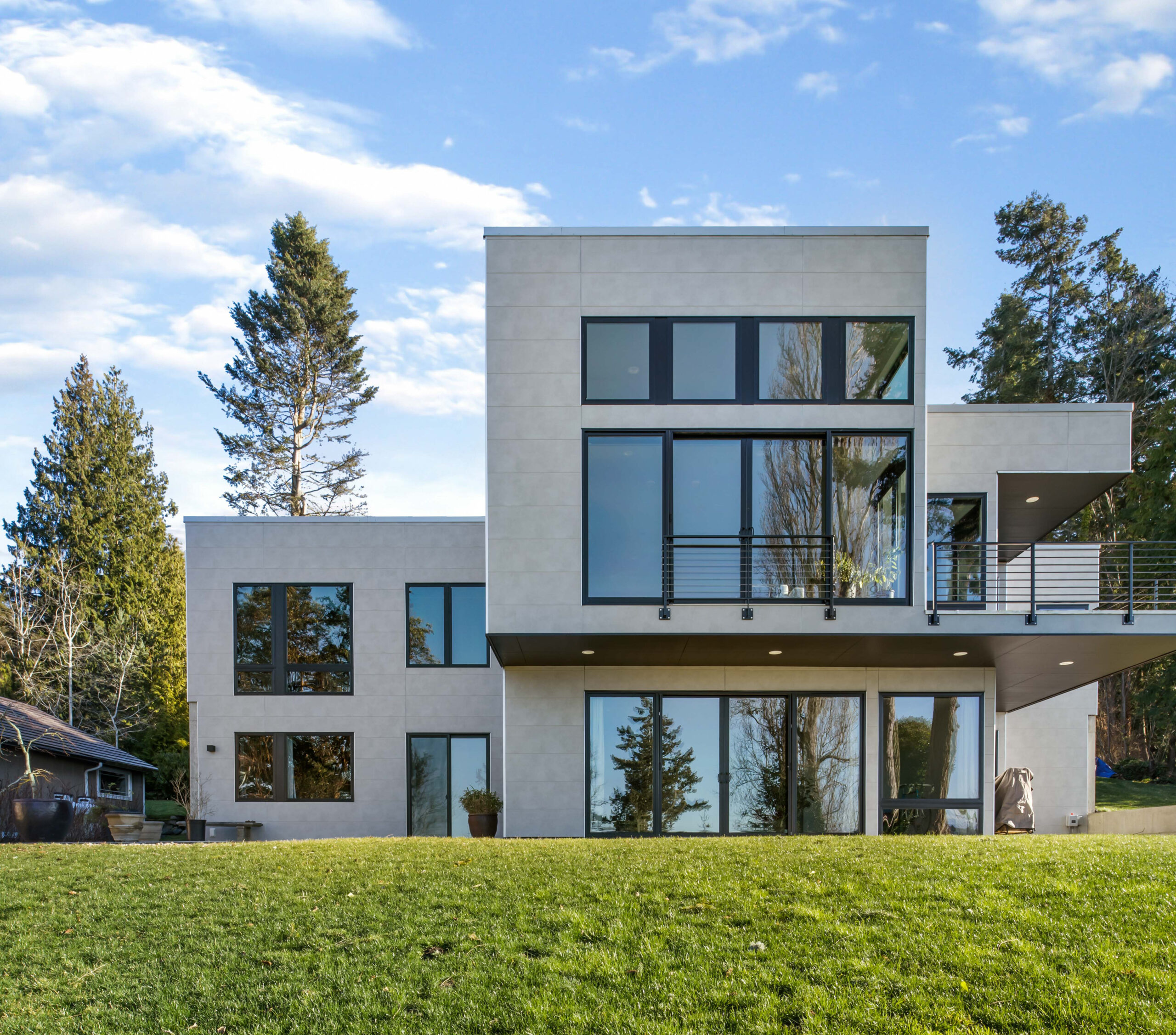 Modern two-story home with light gray wall panels and large windows