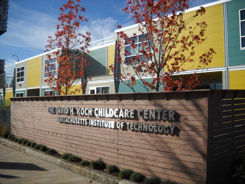 The sign for The David H. Koch Childcare Center at MIT with their yellow and blue building utilizing Nichiha’s modular construction.