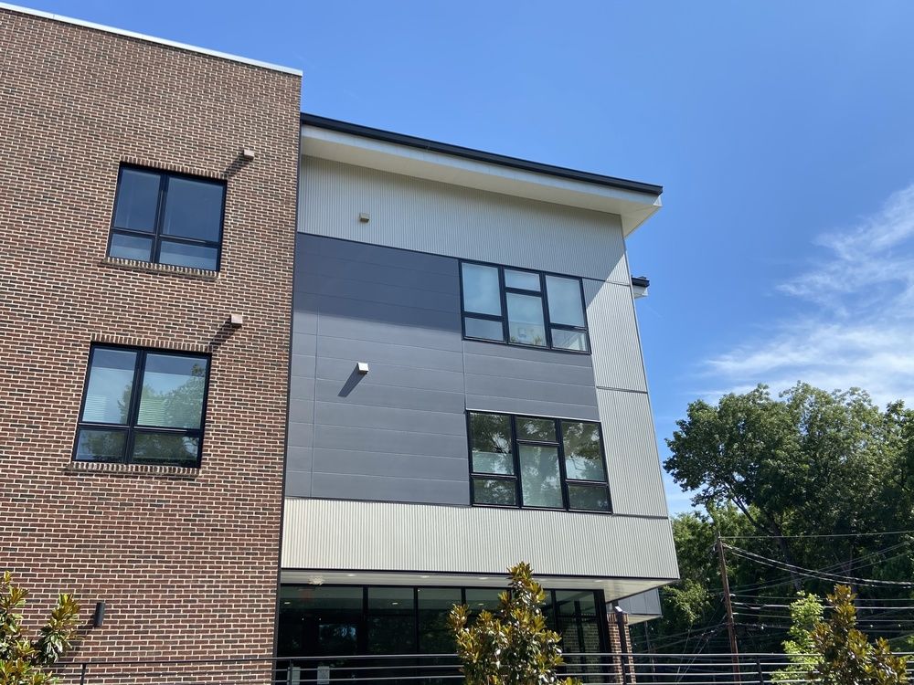 A multi-storied building with mixed brick and gray fiber cement siding.