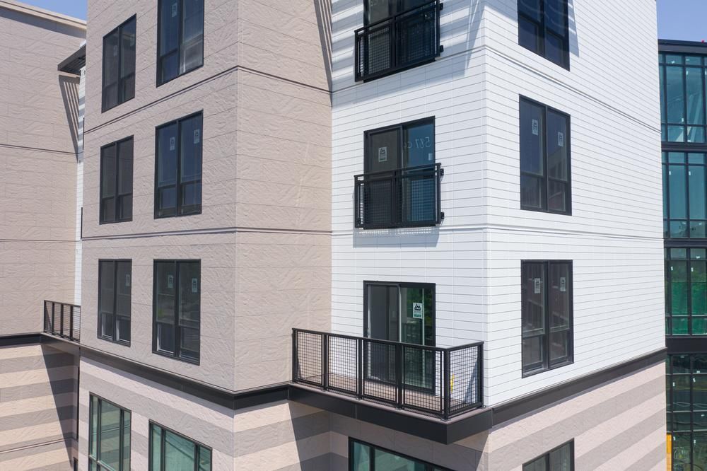 This large complex has white and tan siding. There are a couple of balconies and various rectangular windows on each side of the building.