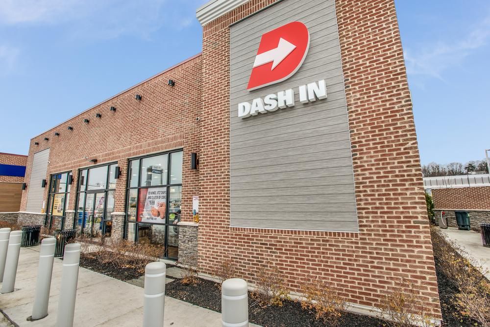 A close-up shot of Dash In convenience store with a logo of a white arrow over a red D, with Nichiha’s fiber cement cladding from their VintageWood series around it.