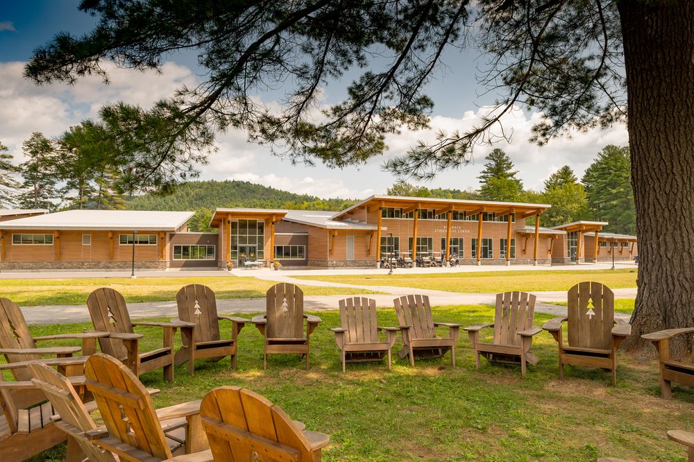 A student life center with Nichiha&rsquo;s VintageWood fiber cement cladding in the background with a circle of rustic wooden chairs in front of it.