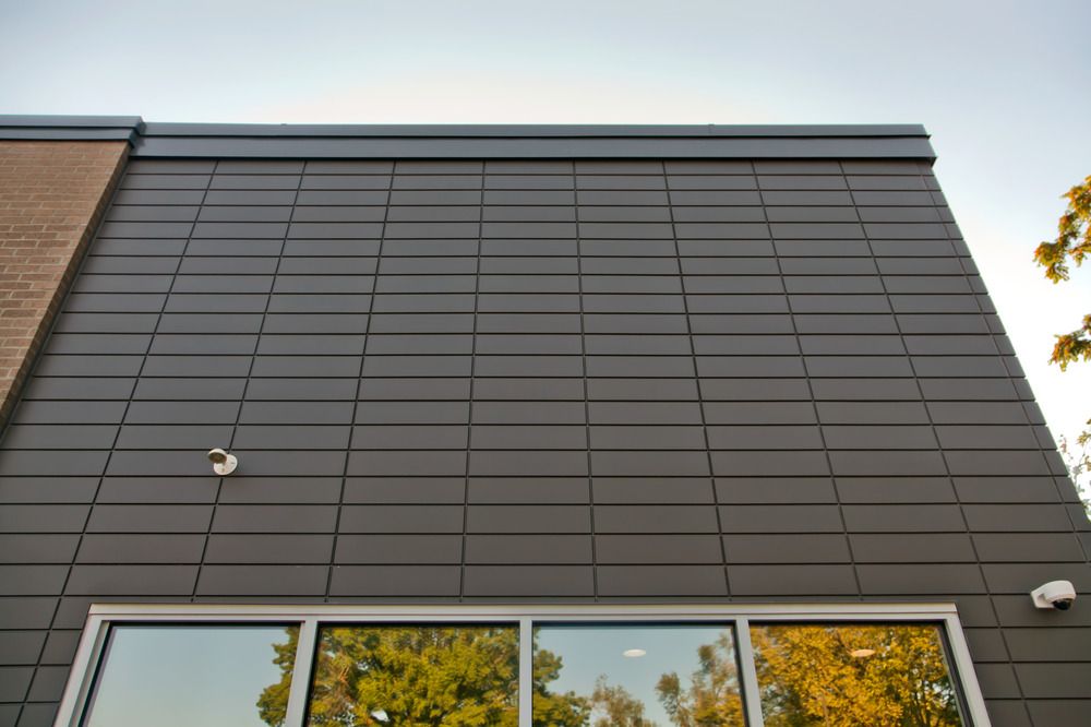 A close-up of Nichiha’s fiber cement cladding on a Firehouse Subs exterior wall. There are snippets of a clean window at the bottom.