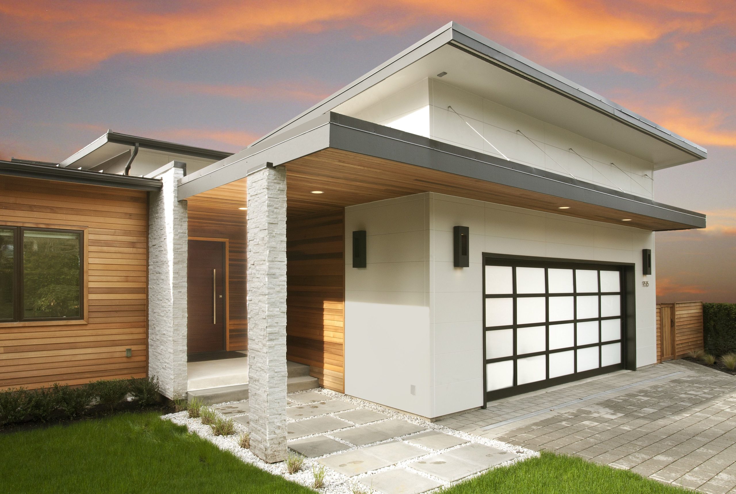 Wood and white cladding make the clean lines of this home's modern architecture stand out against an orange and blue sunset in the background