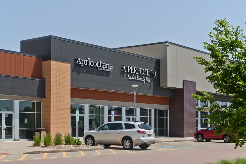 A close-up shot of the strip mall at South Lorraine Place. There are signs for Apricot Lane and A Perfect 10 Nail & Beauty Bar with the exterior utilizing Nichiha’s fiber cement cladding in different textures.