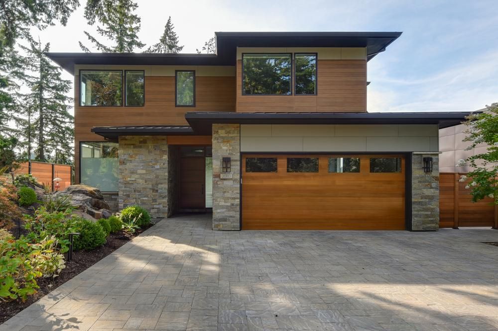 Modern square two-story home with a wooden garage door.