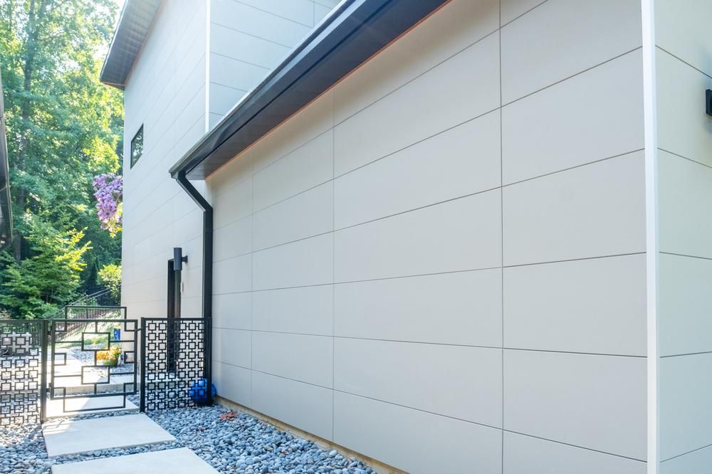 Side of a residential home with large gray fiber cement siding panels.