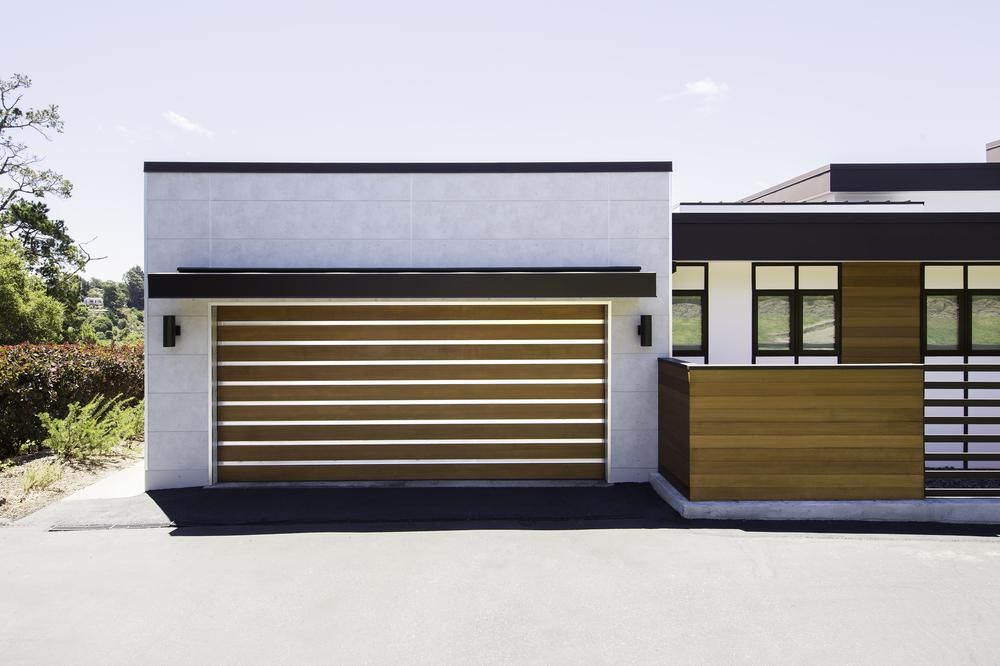 A modern home with white concrete and wood-accented exterior using fiber cement panels that create a linear and minimalist design.