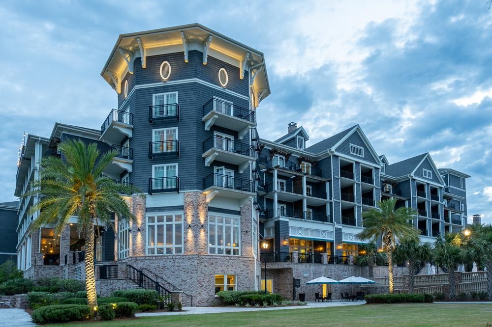 A six story resort with Nichiha Sierra siding in Shadow and white trim. The first two floors have a red/tan brick exterior and the front is landscaped with palm trees.