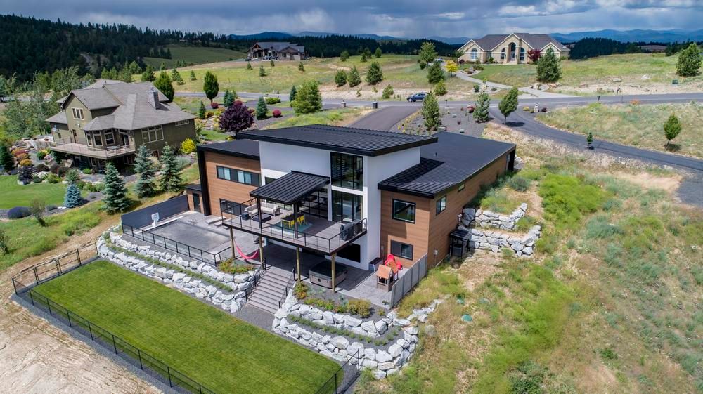 A white, brown and black home with Nichiha fiber cement siding is the center focal point in this photo. There is a cloudy sky, a few neighboring homes and a green lawn surrounding the home.