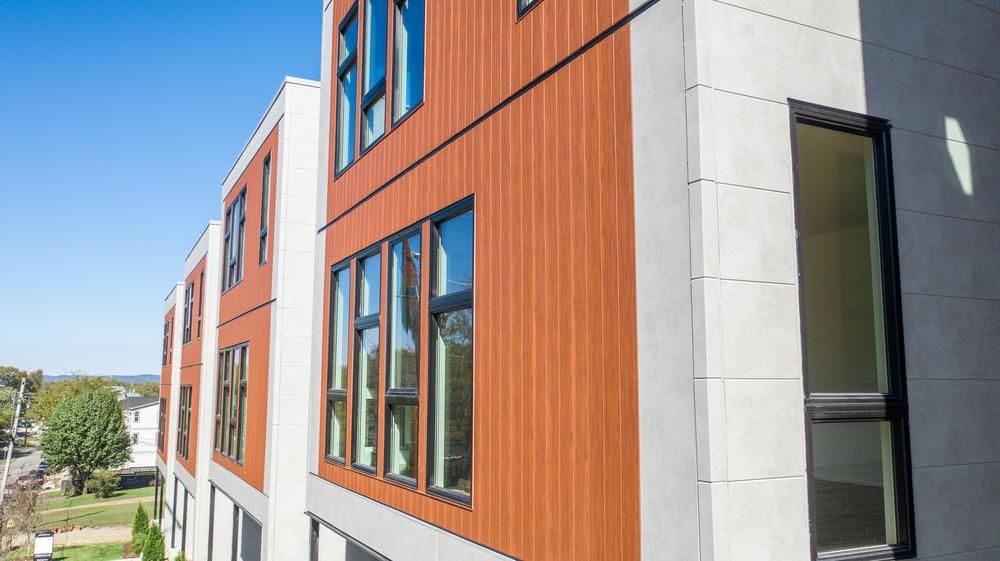 These apartments look out onto a street view. They have vertical wood-like siding.
