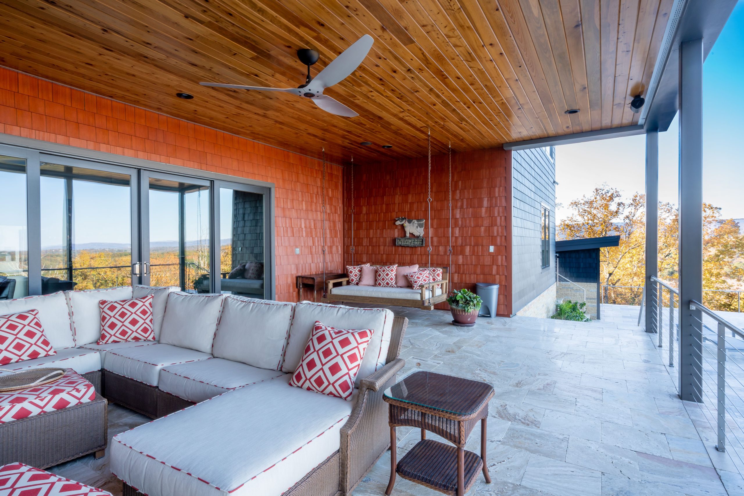Outdoor living space with brown-red shingles siding and a wood-paneled ceiling.